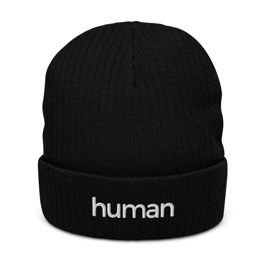 A black ribbed knit beanie with the word 'HUMAN' written on the fold.