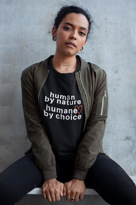woman sitting on stool wearing black nelalena humane by choice sweatshirt under green jacket