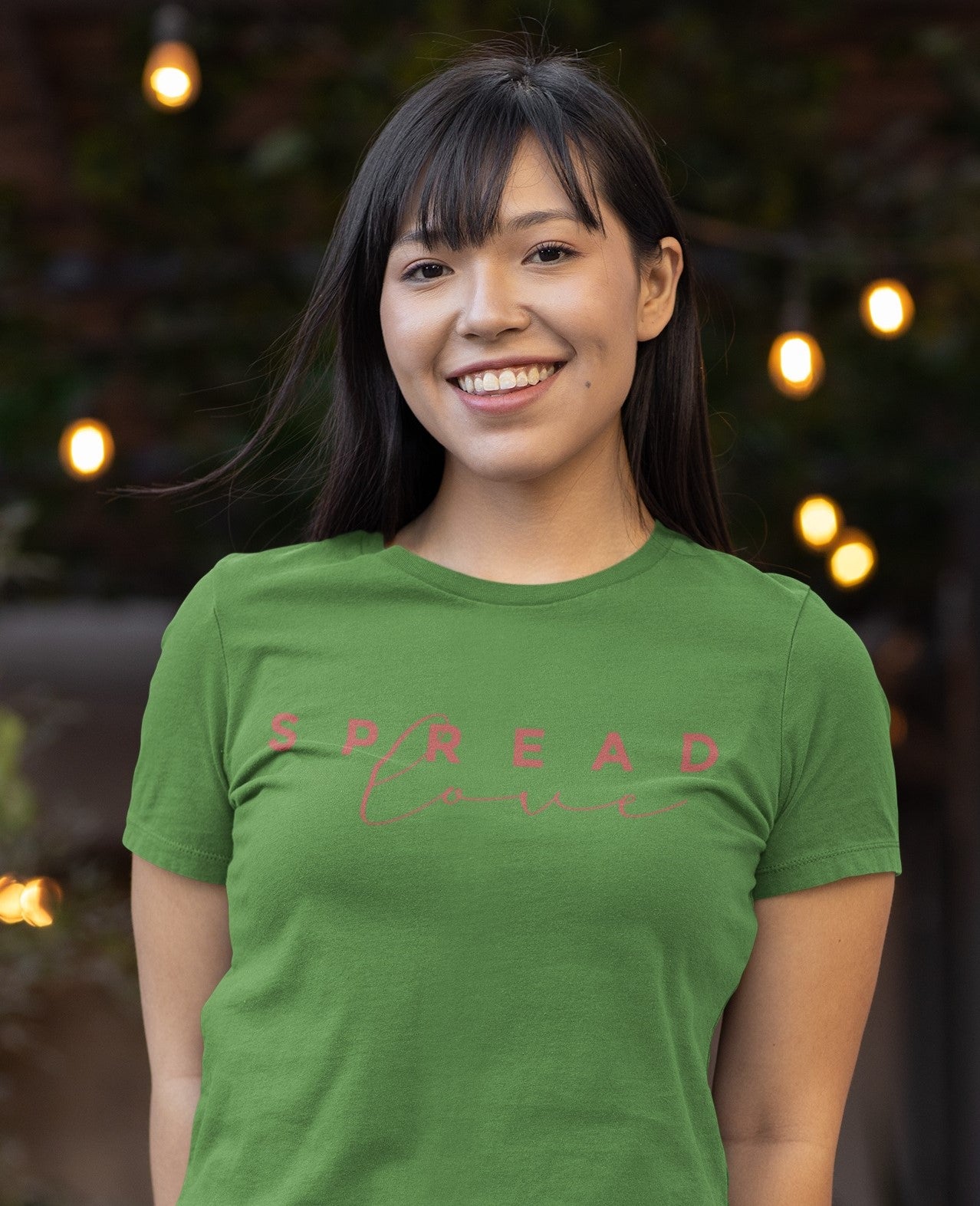 happy woman wearing leaf spread love t-shirt with lights in the background