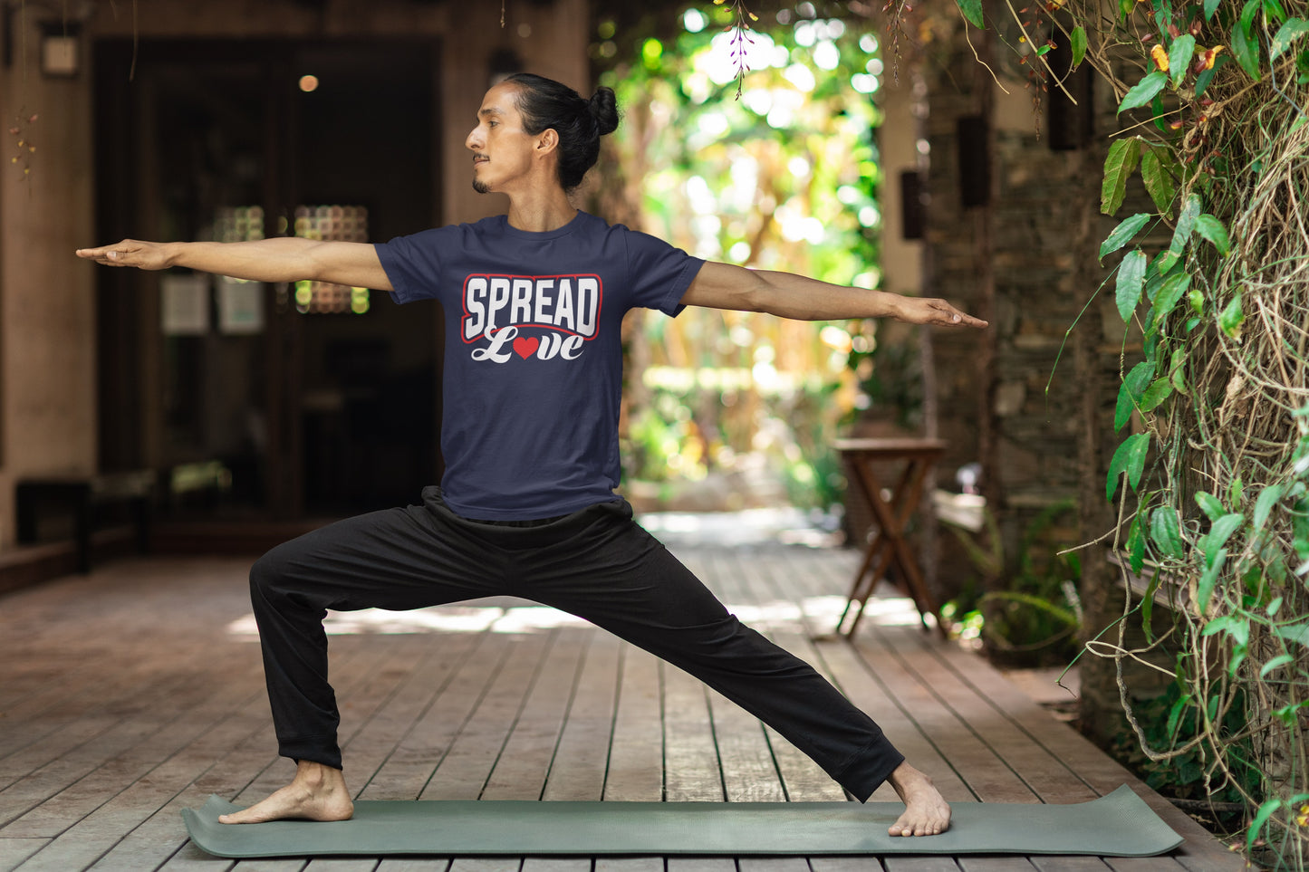 man doing a yoga pose wearing navy blue t-shirt with "spread love" graphic with red heart replacing the "o" 