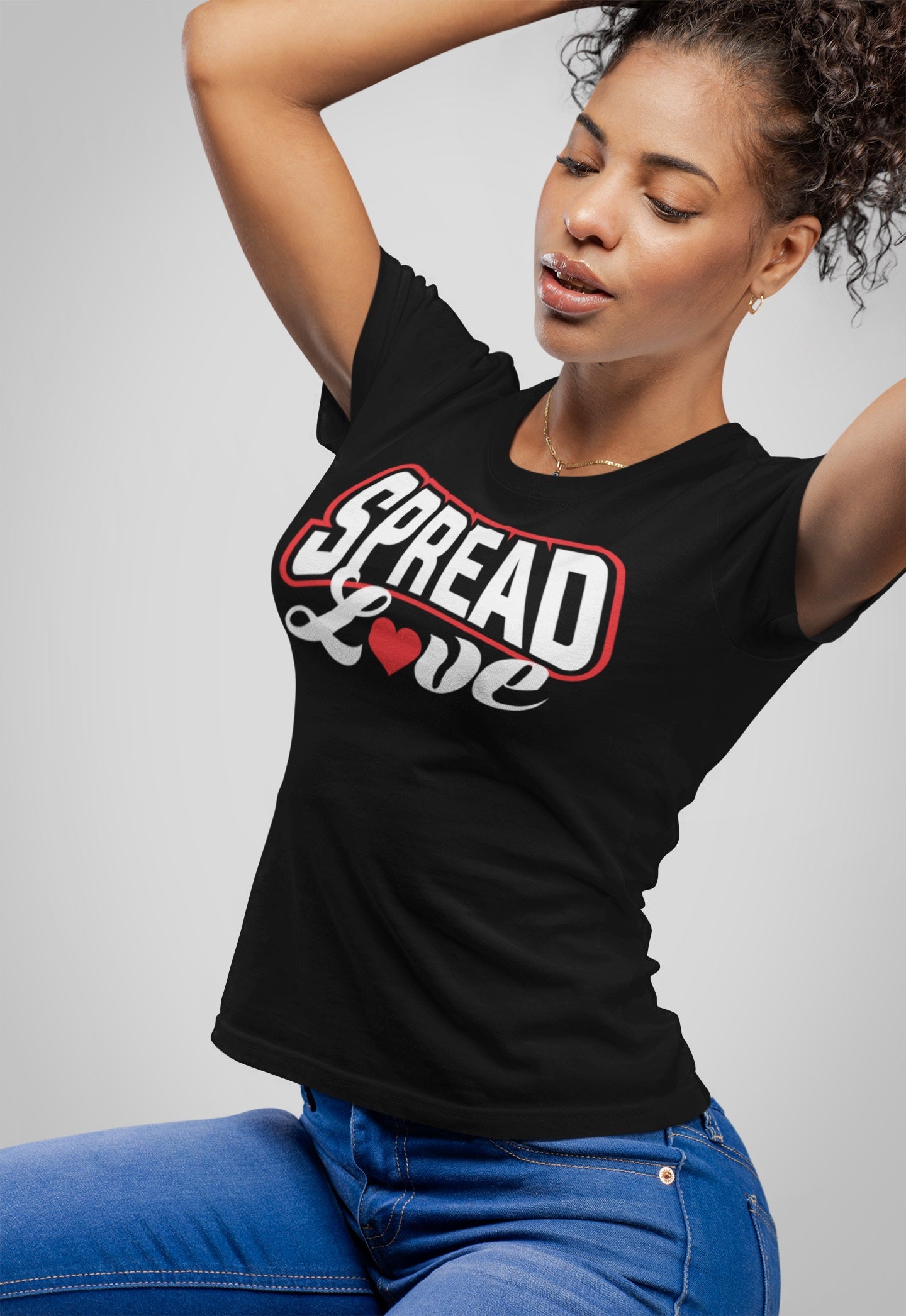 pretty woman fixing her kinky ponytail while wearing a black t-shirt with "spread love" graphic with red heart replacing the "o" 