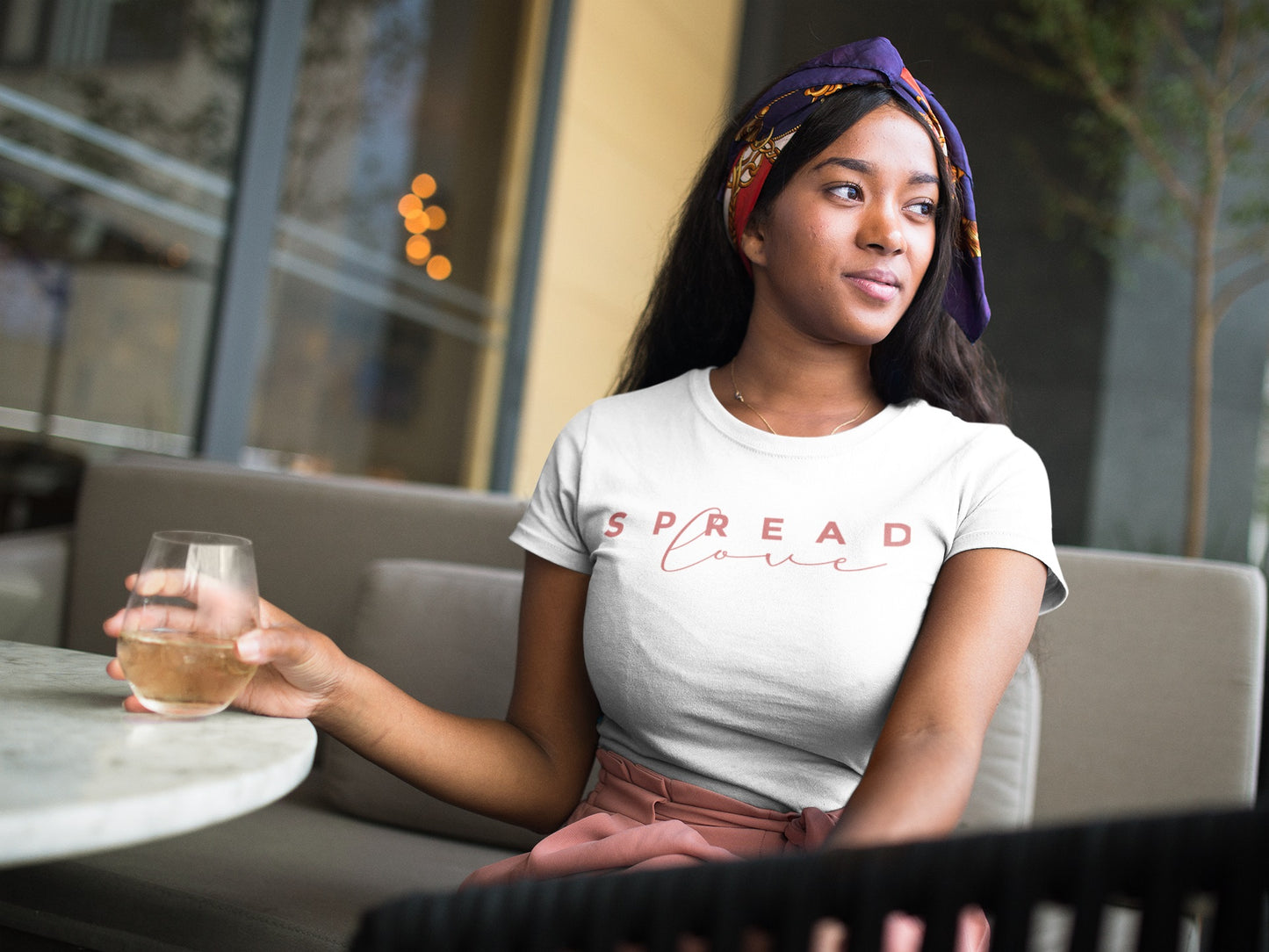 pretty woman having a drink at a terrace while wearing white spread love t-shirt